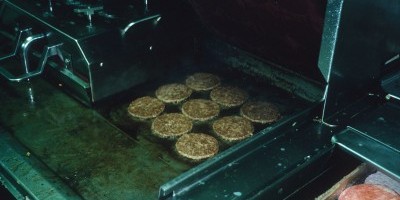 Grill with frozen hamburger patties adjacent.