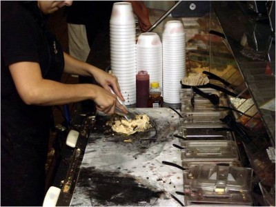 At a store, mix-in ingredients are combined with ice cream to create various customized sundaes and treats.