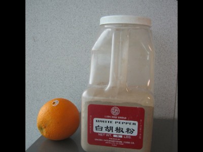 An orange added to illustrate the actual size of a 5lb. container of ground pepper.