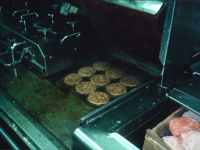 Grill with frozen hamburger patties adjacent.